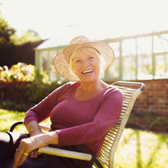 Smiling senior woman sitting outdoors in a sunhat