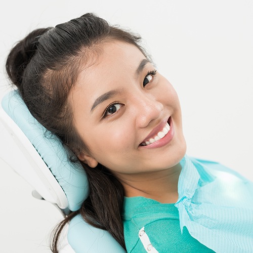 Woman sitting in chair at prosthodontist’s office and smiling