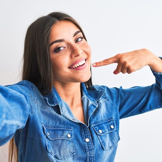 Happy young woman pointing at her beautiful teeth